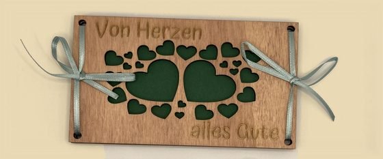 Geldgeschenk aus dunklem Holz mit Herzen und dem Text Von Herzen alles Gute, mit hellblauer Schleife